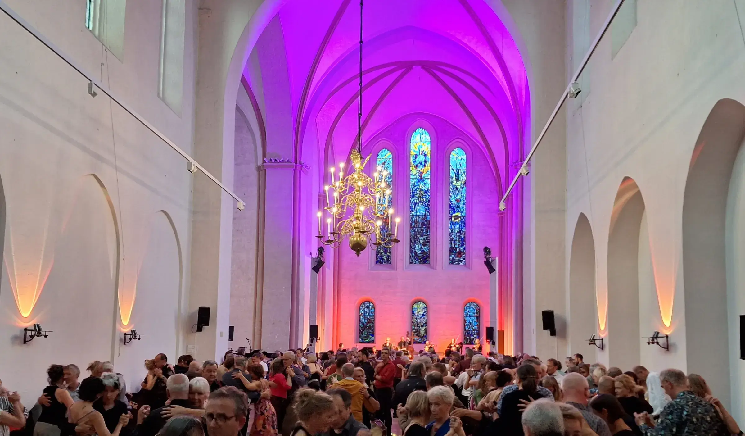 Tanzende Paare bei einer Milonga im violett illuminierten Kirchenschiff der Kulturkirche St. Stephani